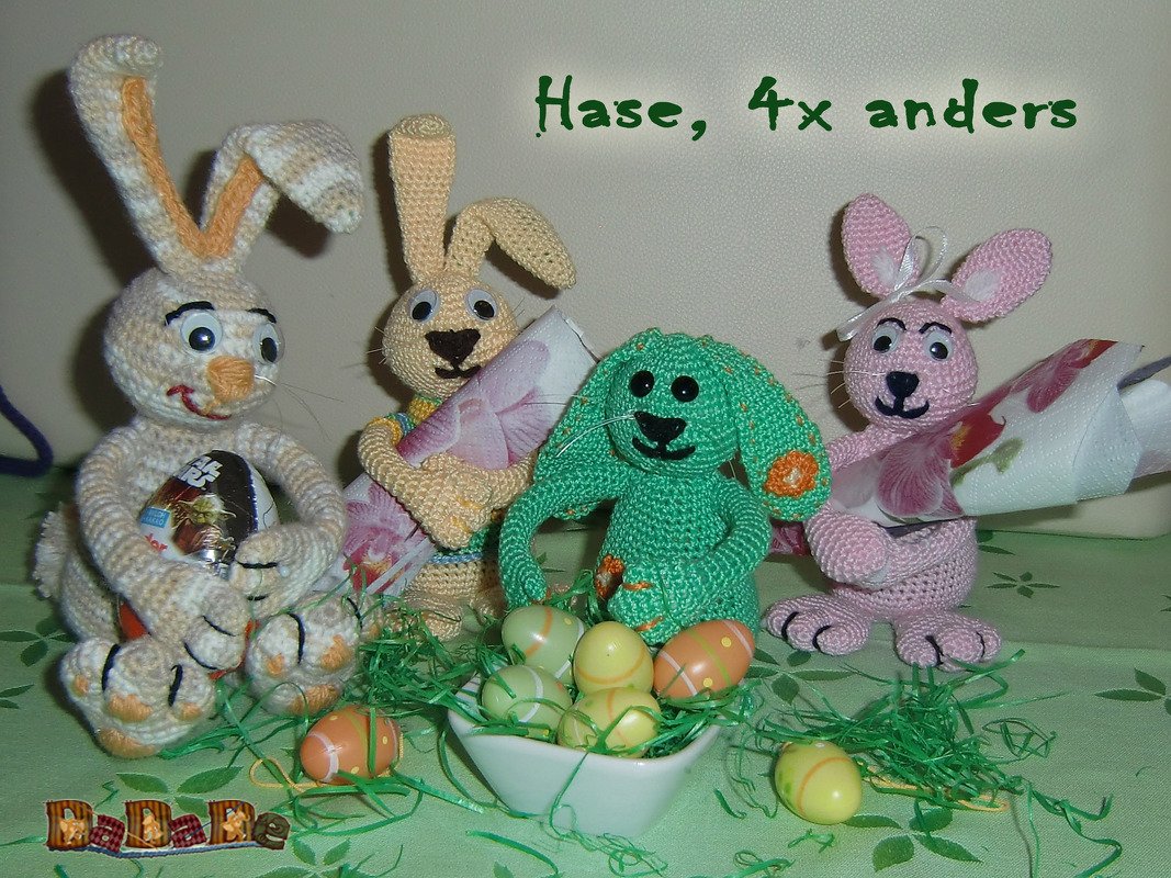 Vier pastellfarbene Amigurumi-Hasen um eine Schale mit Ostereiern und grünem Papiergras
