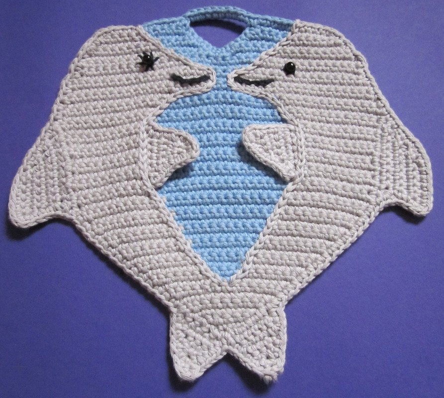 Zwei gehäkelte Topflappen in Delfinform, hellgrau mit blauem Innenfeld und Aufhängeschlaufe