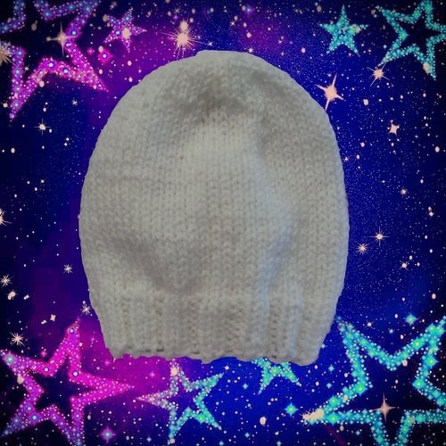 Weiße gestrickte Babymütze mit geripptem Bündchen vor sternenhaftem Hintergrund