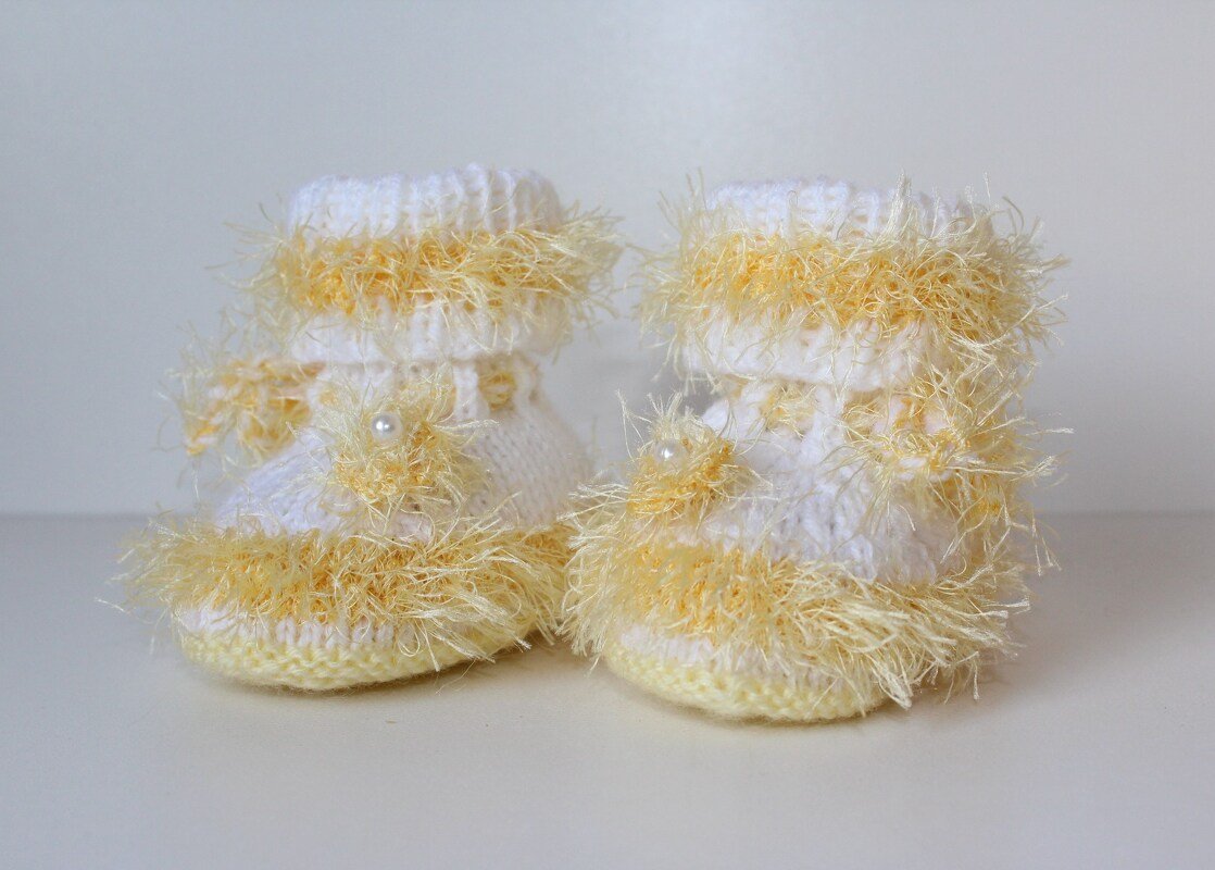 Weiß-gelbe gestrickte Babyschuhe mit flauschigem Garn und Perlen