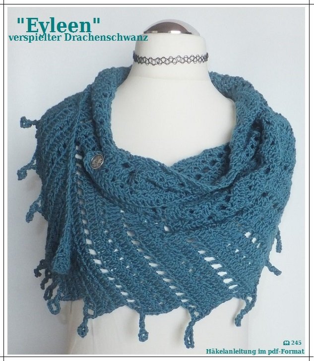 Petrolfarbener, gehäkelter Drachenschwanz-Schal auf Schaufensterpuppe mit Knopf und Fransen.