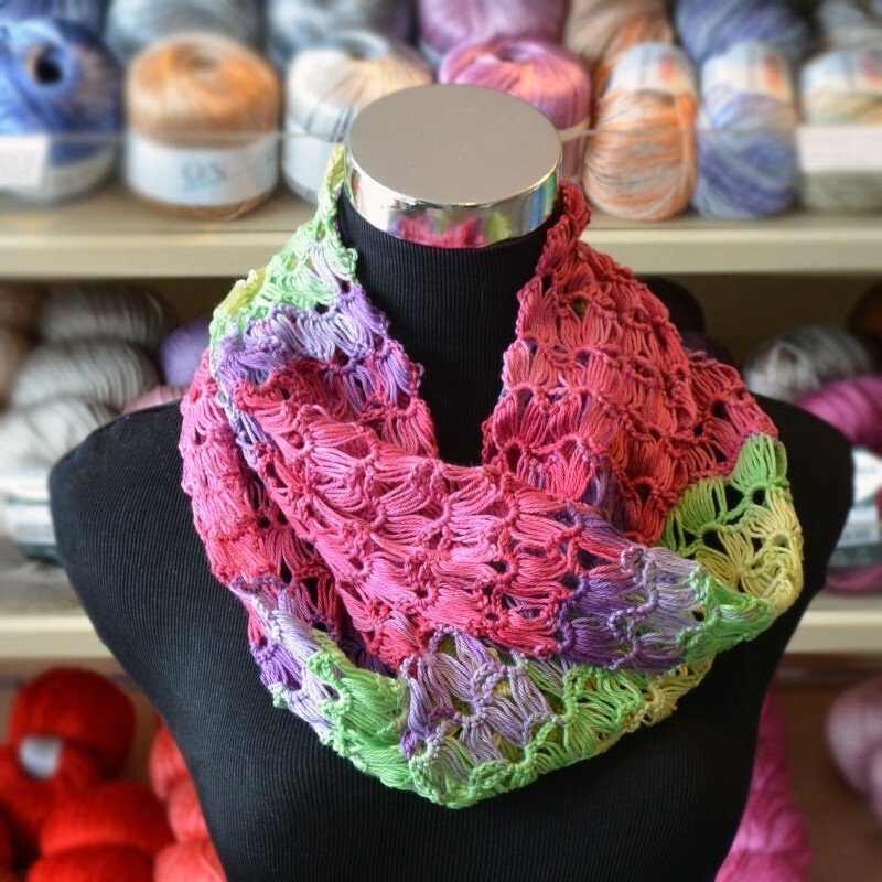 Gehäkelter Loop-Schal in Pink, Lila und Grün mit Ajourmuster auf schwarzer Büste