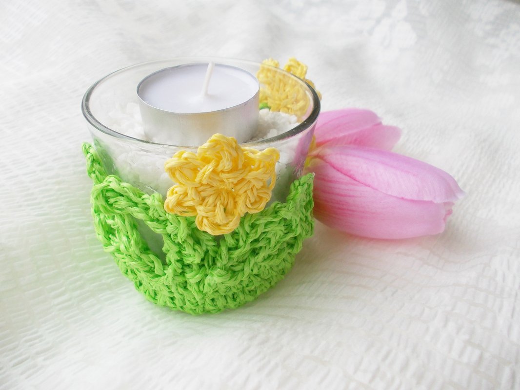 Glaswindlicht mit grünem Häkelbezug und gelben Häkelblüten, rosa Tulpe daneben