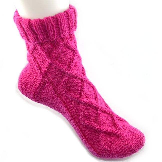 Pinke gestrickte knöchellange Damensocke mit Zopfmuster auf weißem Hintergrund