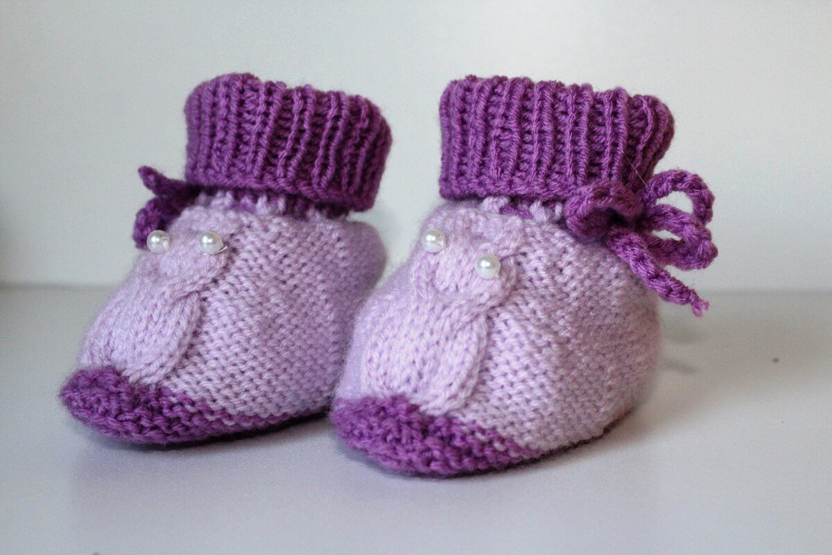 Lila gestrickte Babyschuhe mit Zopfmuster, Perlen und geripptem Umschlag