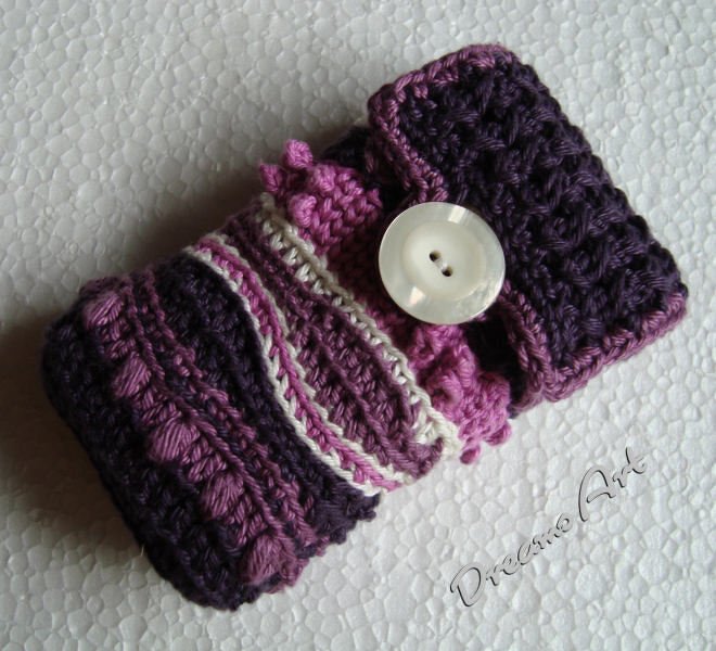 Gehäkeltes Utensilo in Lila- und Violetttönen mit strukturierten Mustern und weißlichem Knopf.