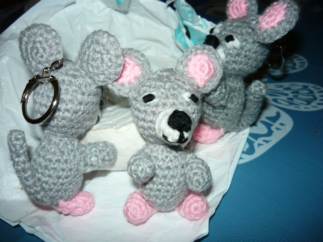 Drei gehäkelte Amigurumi‑Mäuse in Grau mit rosa Ohren und Pfoten; eine mit Schlüsselring.