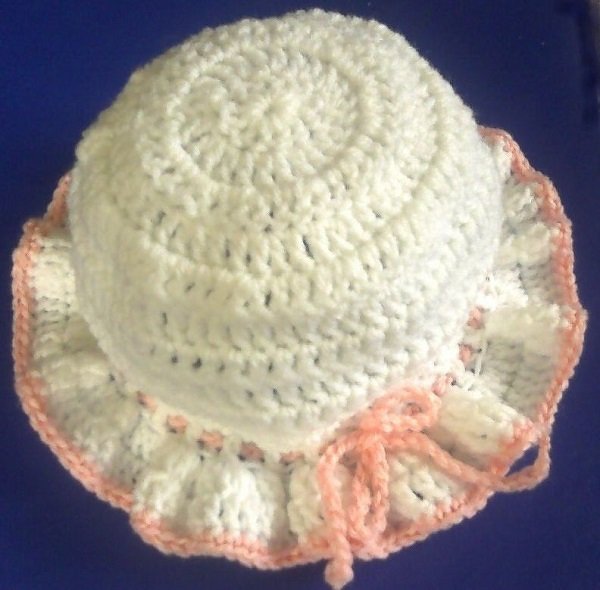 Weiße gehäkelte Babymütze mit rosa Rüschenrand und Bindekordel