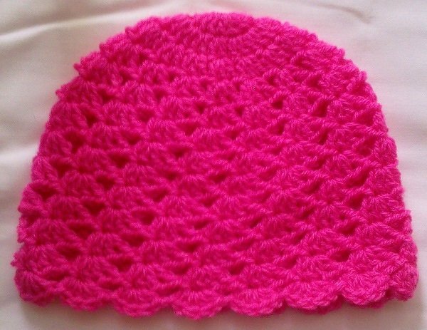 Gehäkelte Babymütze in leuchtendem Pink mit Muschelmuster und gewelltem Rand