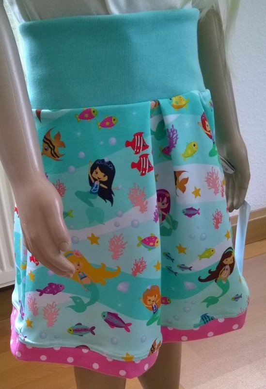 Türkiser Kinderrock mit Meerjungfrauen- und Fischmotiv, breites Bündchen und rosa Punktsaum
