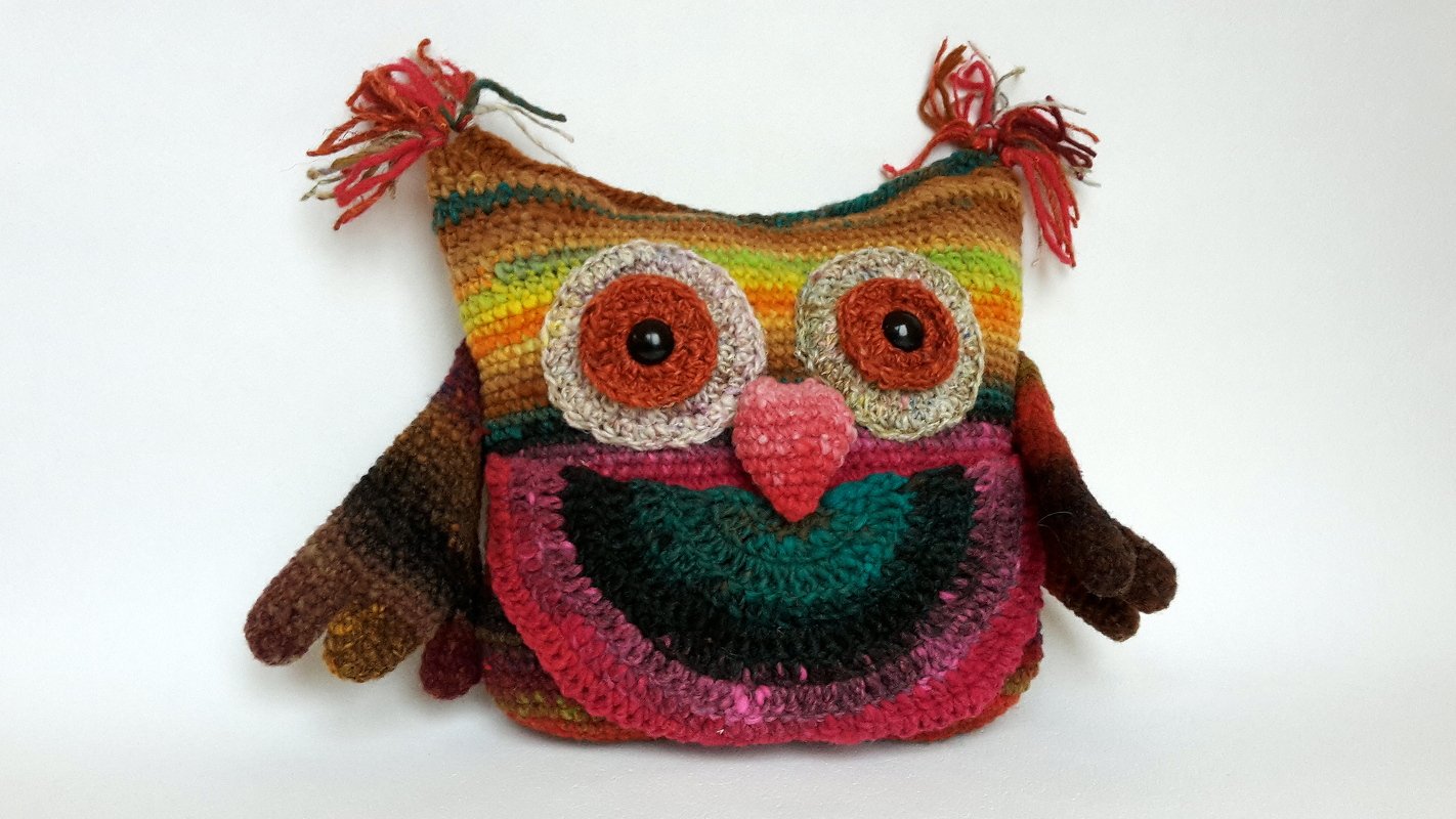Gehäkeltes Eulen-Kissen mit bunten Streifen, großen Augen und Quasten