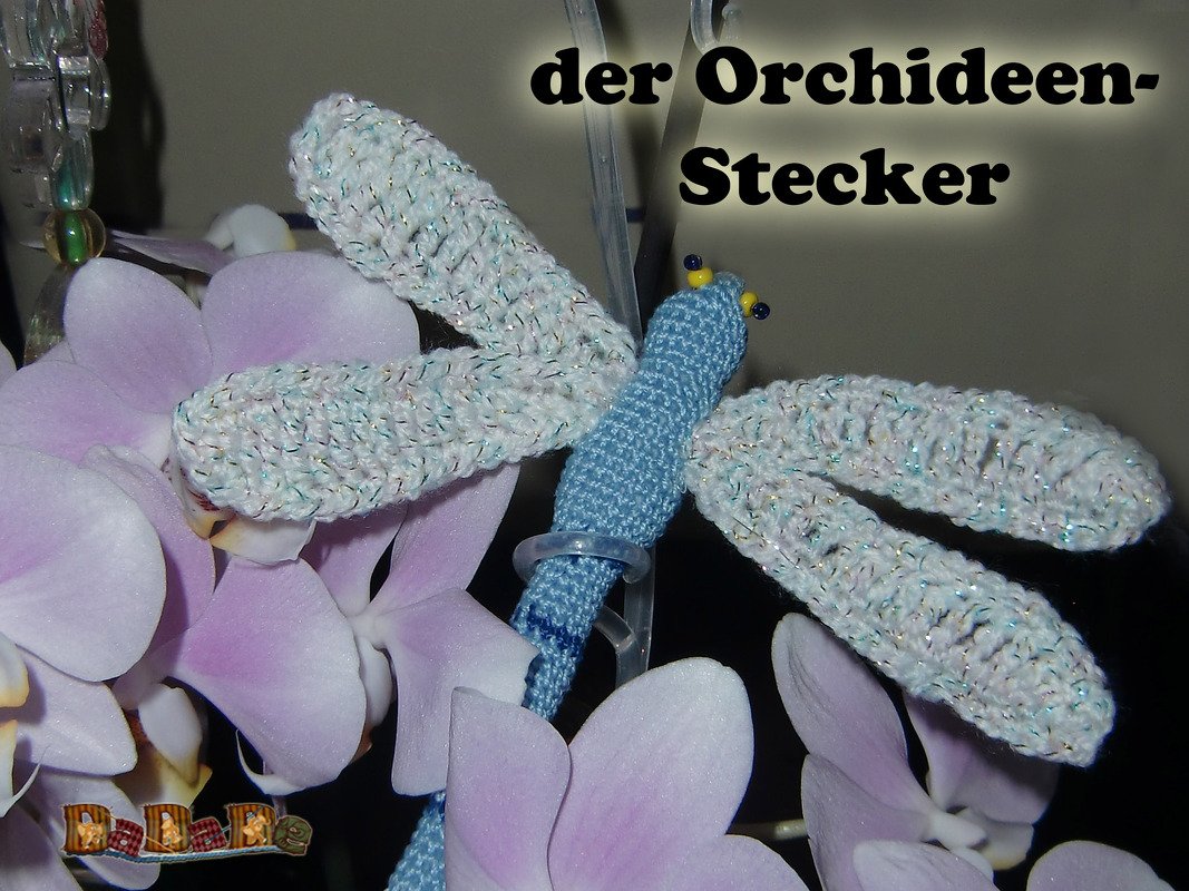 Hellblaue gehäkelte Libelle mit schimmernden weißen Flügeln am Orchideenstängel