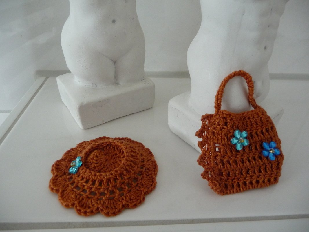 Kleiner gehäkelter Puppenhut mit Muschelrand und braune Mini-Handtasche, verziert mit blauen Perlenblüten