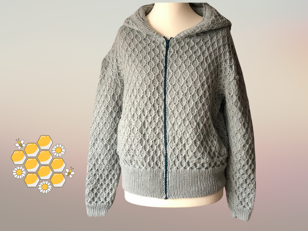 Hellgraue gestrickte Damen-Kapuzenjacke mit Reißverschluss und Wabenmuster auf einer Schaufensterpuppe.