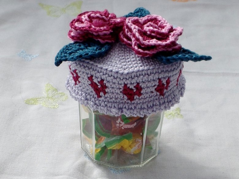 Gehäkelte lavendelfarbene Glasabdeckung mit rosa Rosen und petrolfarbenen Blättern