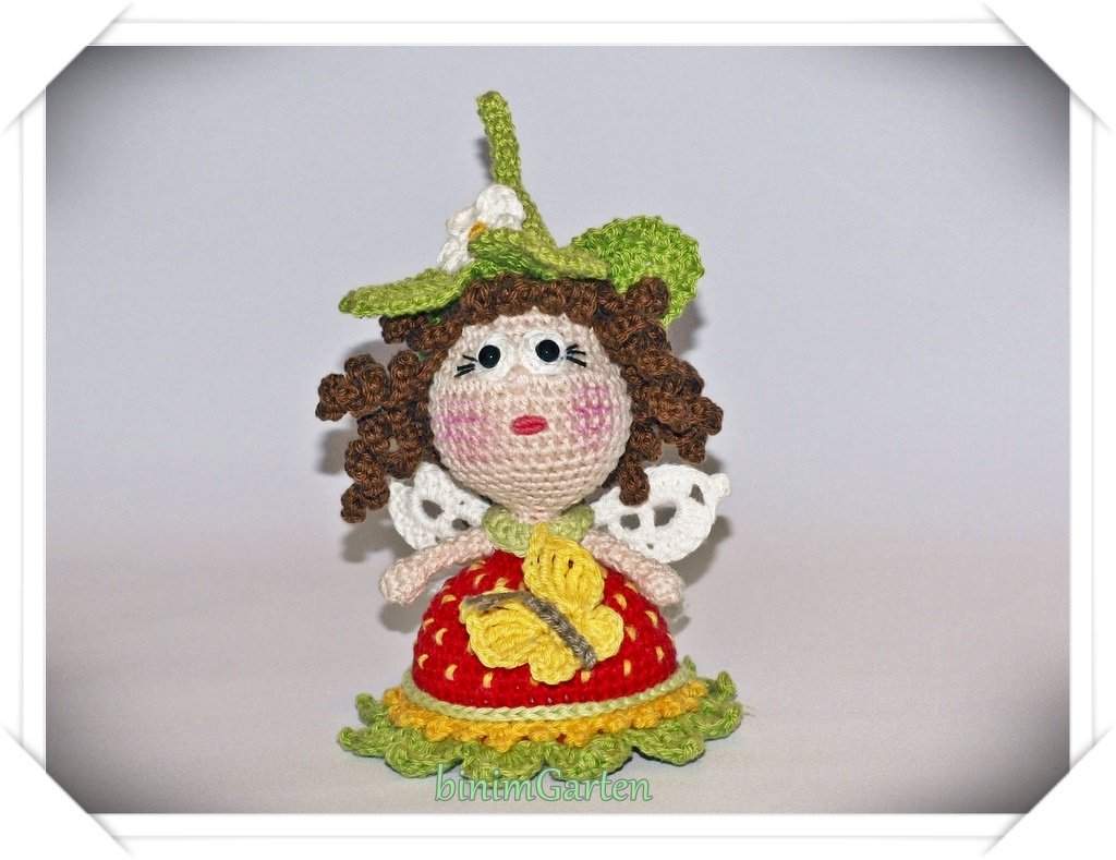 Gehäkelte Amigurumi-Puppe mit grünem Blatt-Hut, weißen Flügeln und gelbem Schmetterling