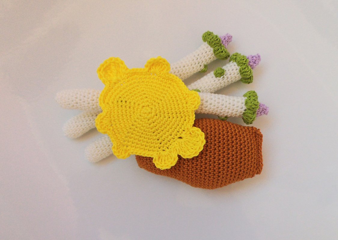 Verschiedene gehäkelte Amigurumi-Bestandteile: gelbe Blüte, weiße Stängel, braunes Körperteil
