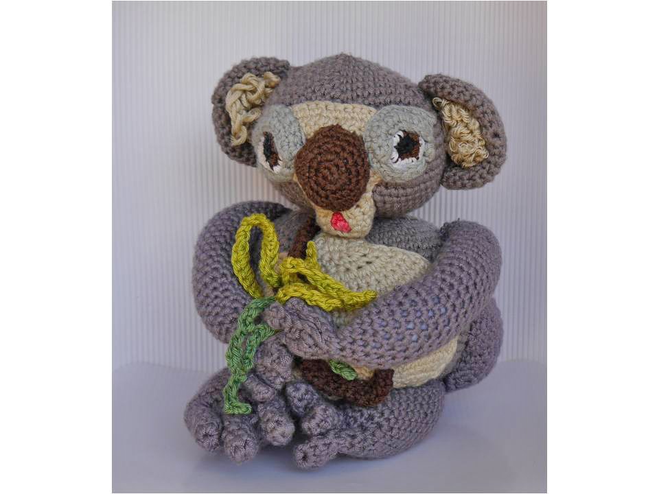Gehäkelter Koala in Grau und Beige hält Eukalyptusblätter