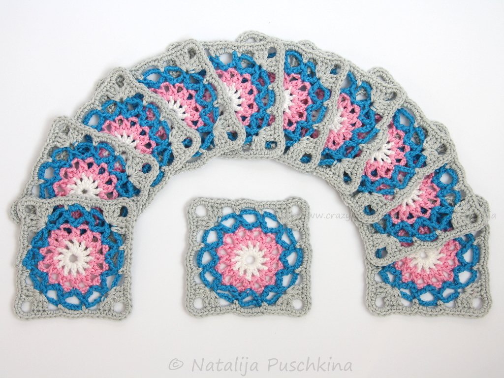 Mehrere gehäkelte Granny Squares in Rosa, Blau und Grau auf weißem Hintergrund