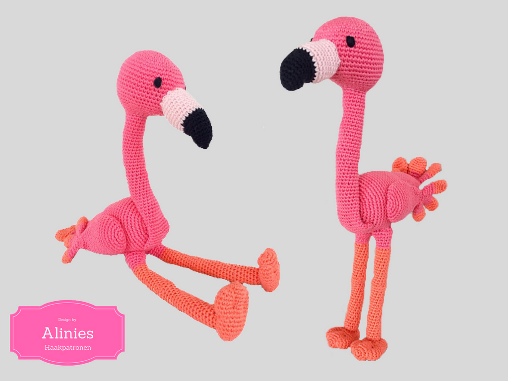 Two crocheted amigurumi flamingos, one seated and one standing, pink bodies with coral-orange legs and black-tipped beaks.