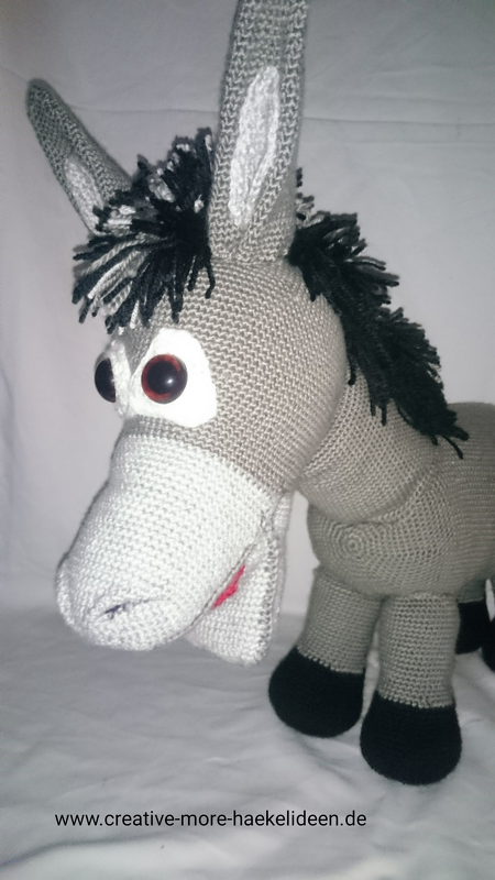 Gehäkelter grauer Amigurumi‑Esel mit schwarzer Mähne und dunklen Augen, dreiviertelansicht
