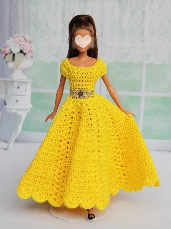 Fashion doll wearing a hand-crocheted yellow dress with a fitted bodice, full scalloped skirt and decorative belt.