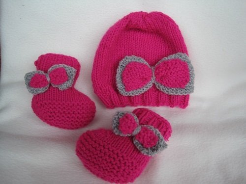 Gestrickte pinke Babymütze und passendes Paar Schühchen mit grauen Schleifen