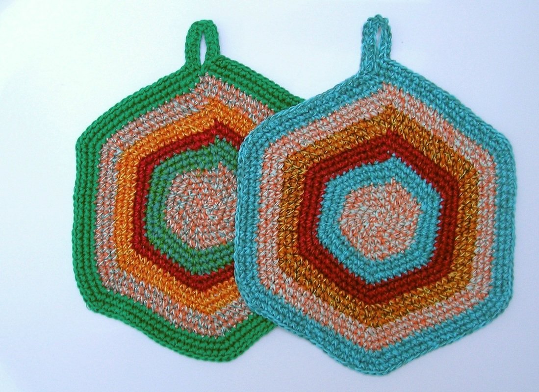 Zwei sechseckige gehäkelte Topflappen mit bunten Ringen und Aufhängeschlaufen