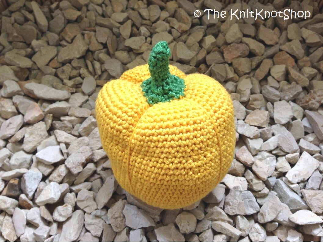 Nahaufnahme einer gehäkelten gelben Paprika mit grünem Stiel