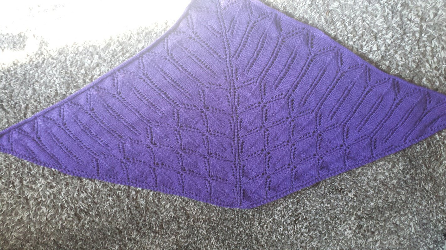 Violettes gestricktes Dreieckstuch mit Ajour-Blattmuster und Mittelreihe auf grauem Teppich