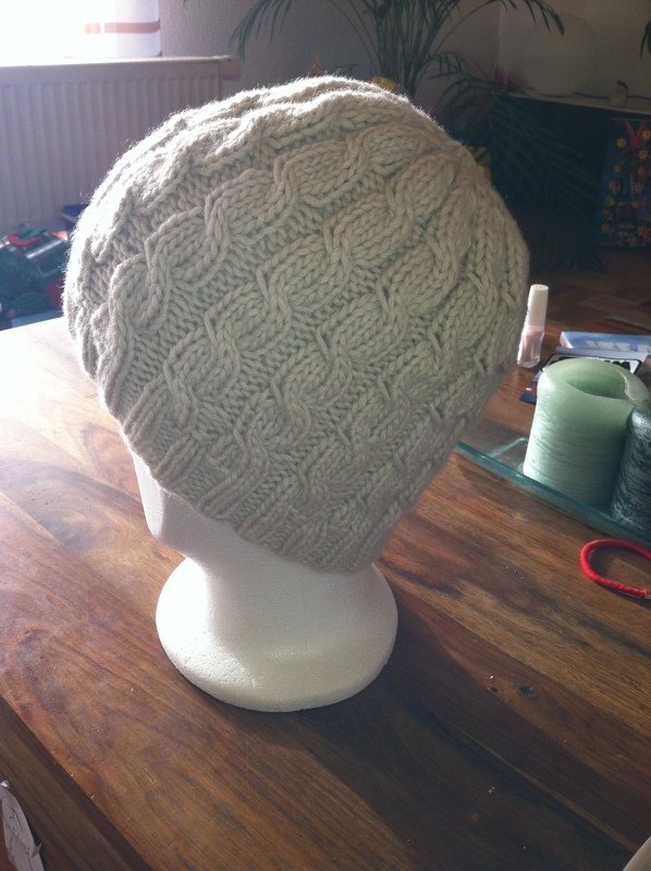 Beige Strickmütze mit Zopfmuster auf weißem Kopfmodell