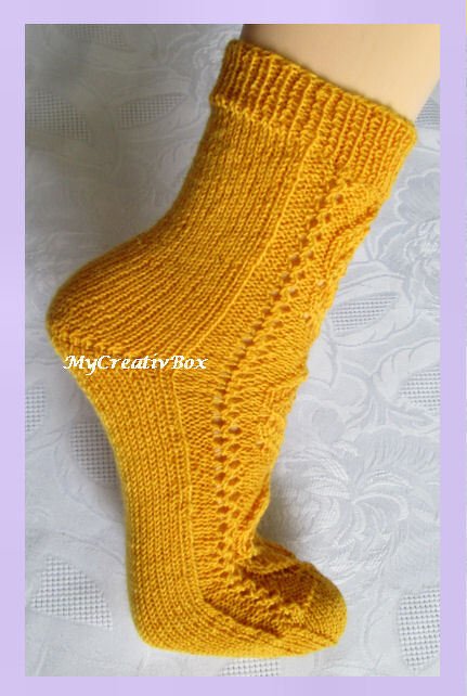 Gelbe gestrickte Socke mit seitlichem Ajourmuster auf Fu
Rippenbündchen