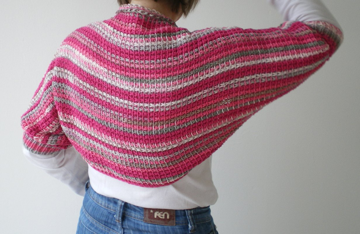 Nahaufnahme Rückenansicht eines kurzgeschnittenen, gestreiften Häkelboleros in Pink, Grau und Weiß
