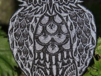 Nahaufnahme einer gestickten Eulen-Applikation in Schwarz und Grau mit feinen Mustern