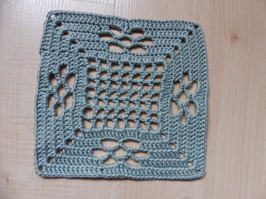 Gehäkeltes Granny Square in Minzgrün mit offenem Gittermuster auf hellem Holzuntergrund