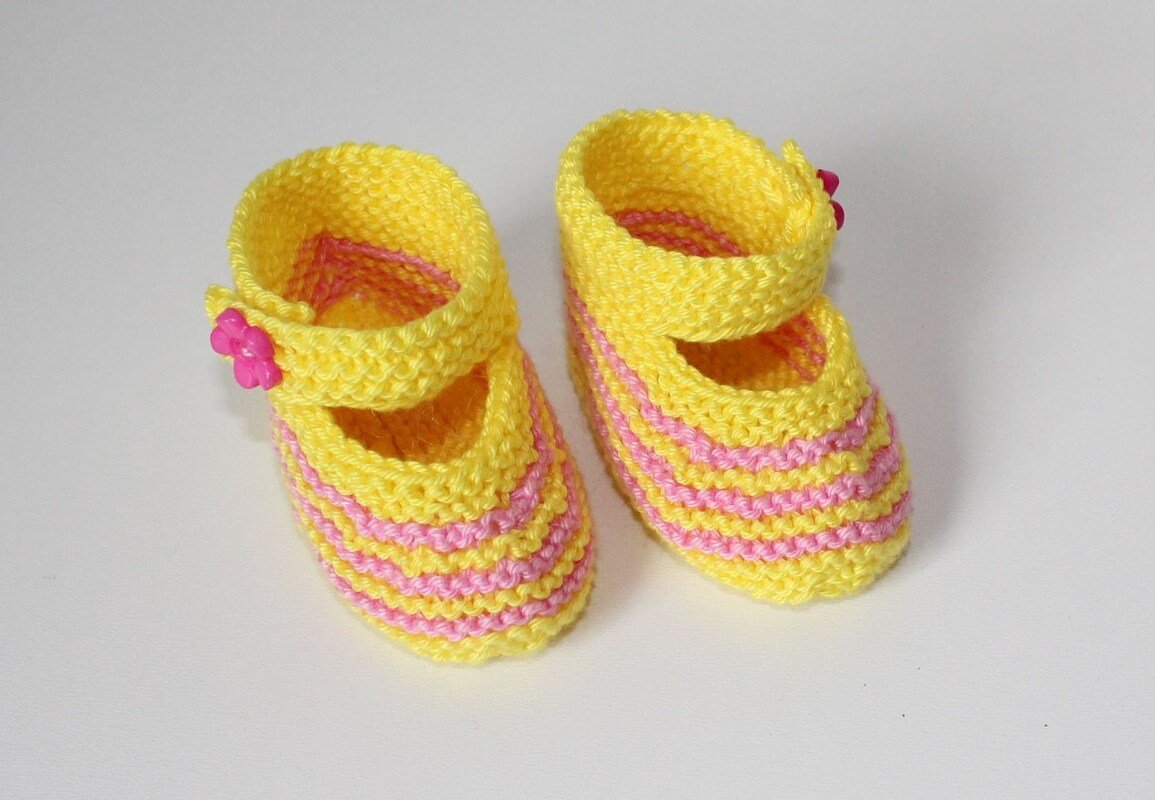 Gestrickte gelbe Babyschuhe mit rosa Streifen und Riemchen, Blütenknopf