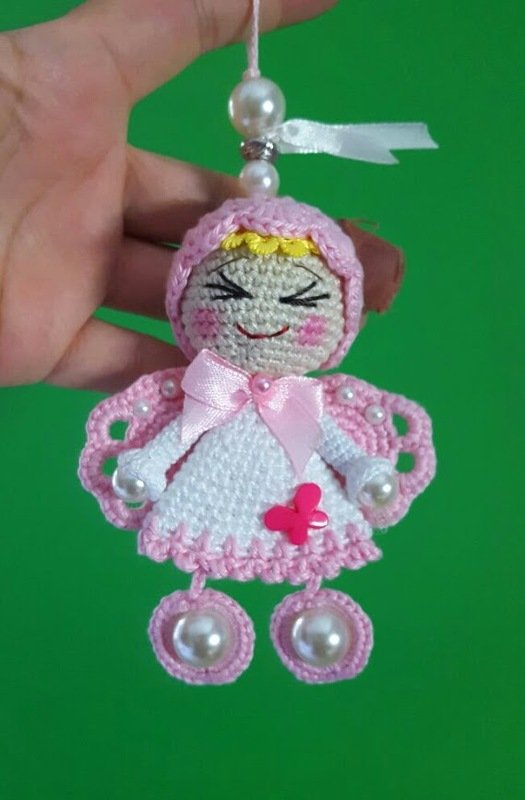 Gehäkelter Amigurumi-Engel in rosa und weiß mit Perlen, Schleife und gesticktem Gesicht an einer Aufhängeschnur
