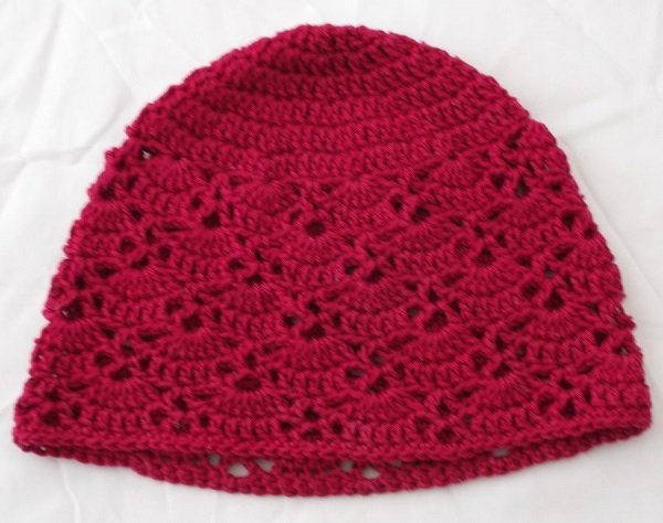 Gehäkelte Kinder-Mütze in dunkelpink mit einfachem Muschelmuster, flach liegend
