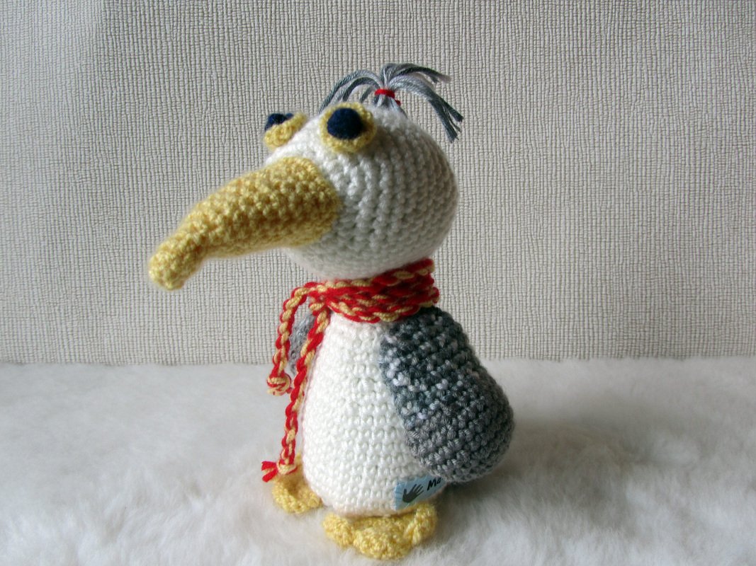 Handgehäkelter Amigurumi-Vogel weiß grau gelb mit gestreiftem Schal
