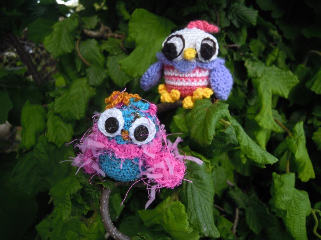Zwei gehäkelte Amigurumi-Eulen auf einem Ast, die ihre Details wie Form, Augen und Garnstrukturen deutlich zeigen.