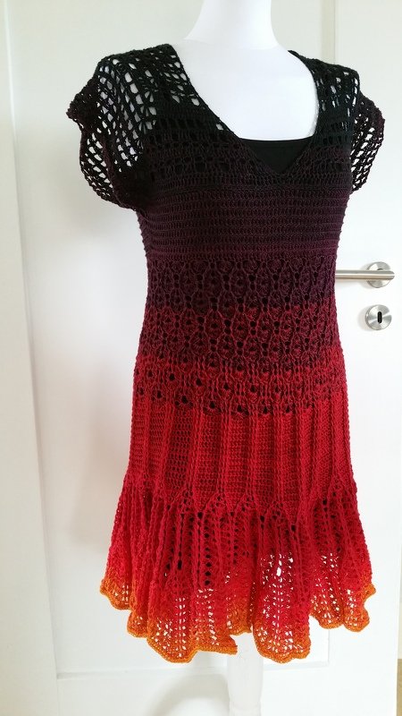 Mannequin trägt gehäkeltes Damenkleid mit Ombre‑Farbverlauf in Schwarz, Rot und Orange