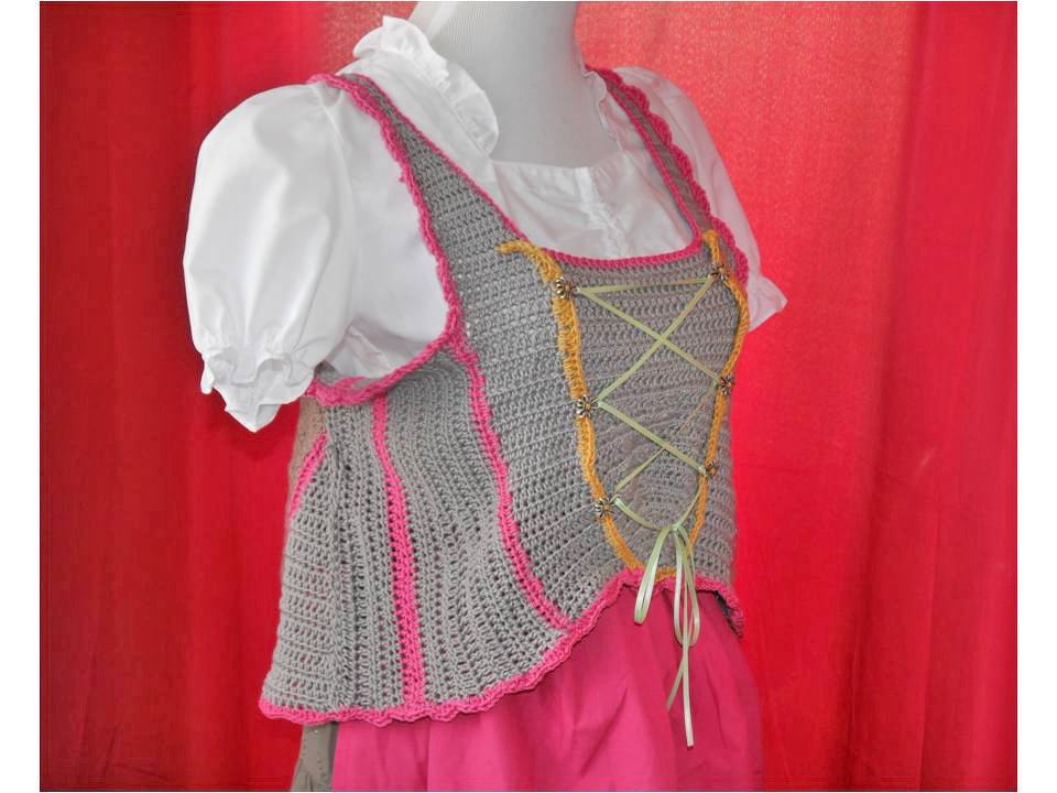 Gehäkelte graue Weste mit pinken Kanten, hellgrüner Kreuzschnürung und zierlichen Metallperlen an einer Schaufensterpuppe.
