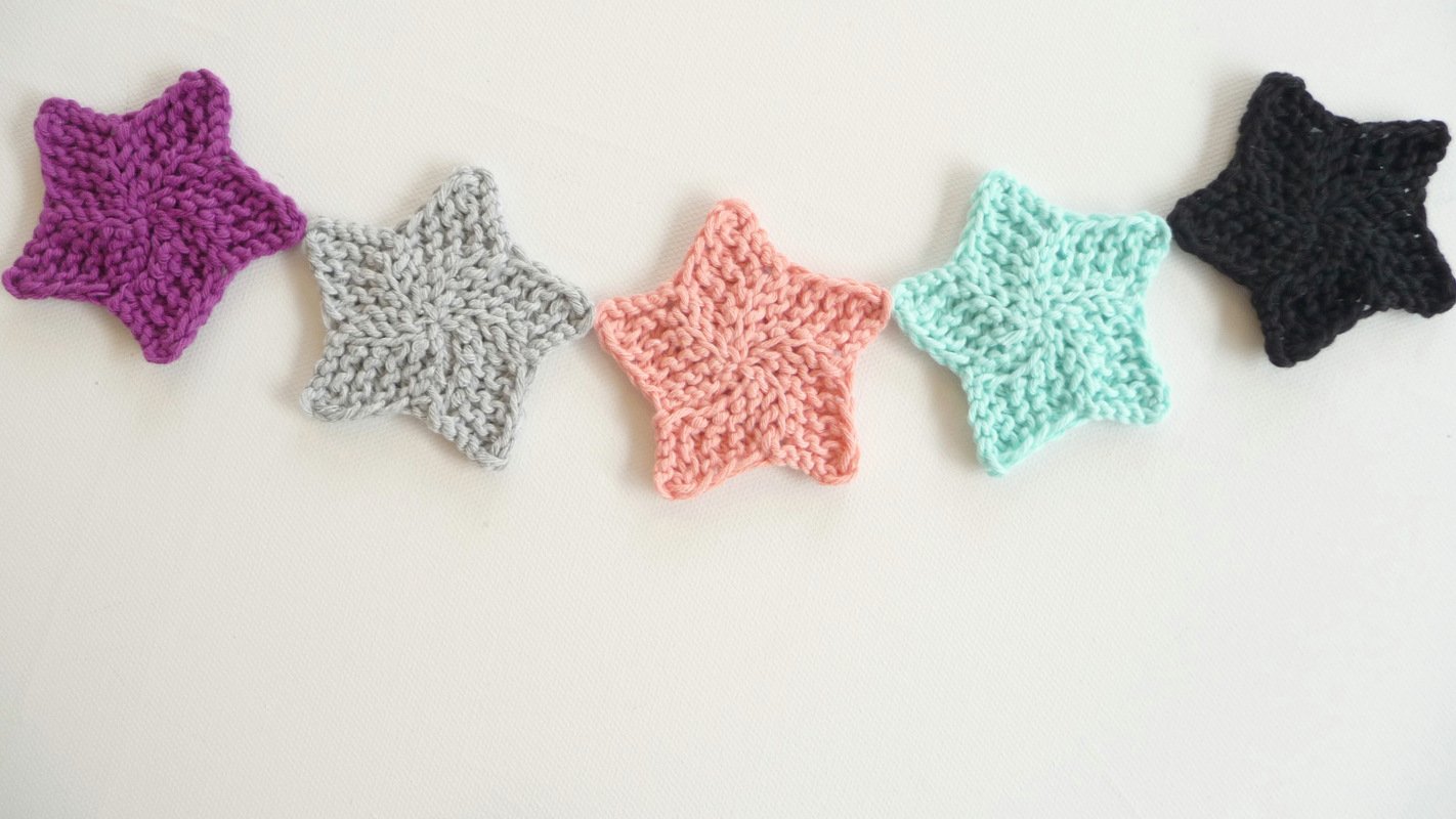 Fünf bunte gestrickte Sterne als Applikationen auf hellem Hintergrund