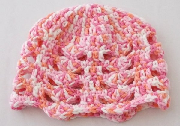 Gehäkelte Mütze für Babys in Rosa, Orange und Weiß mit Lochmuster und gewelltem Rand.