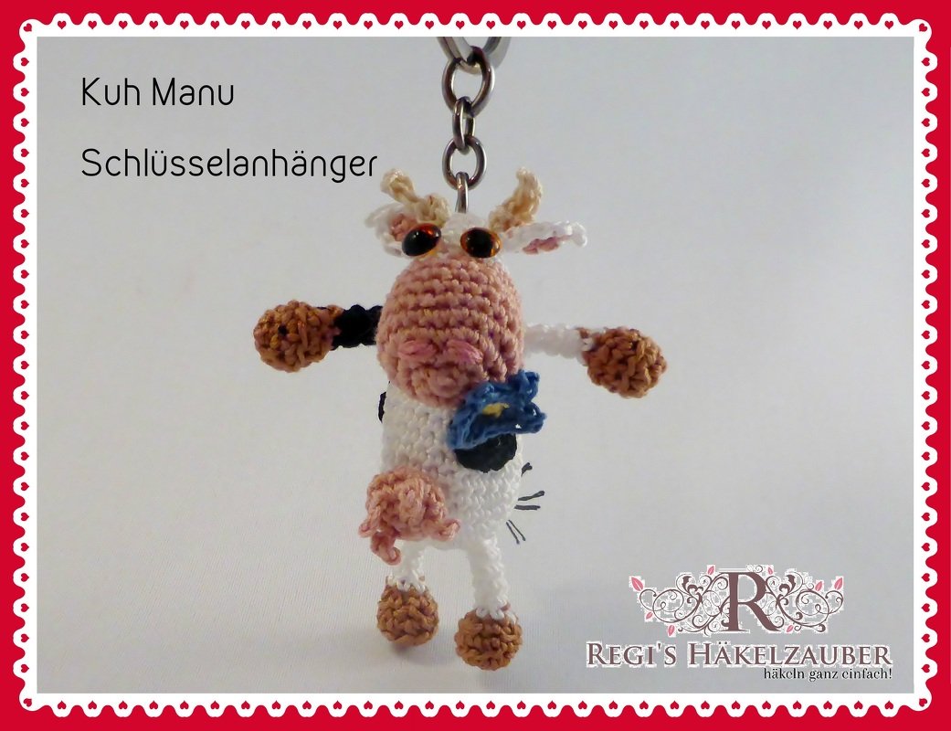 Kleiner gehäkelter Amigurumi Kuh-Schlüsselanhänger mit Metallring und blauem Blümchen