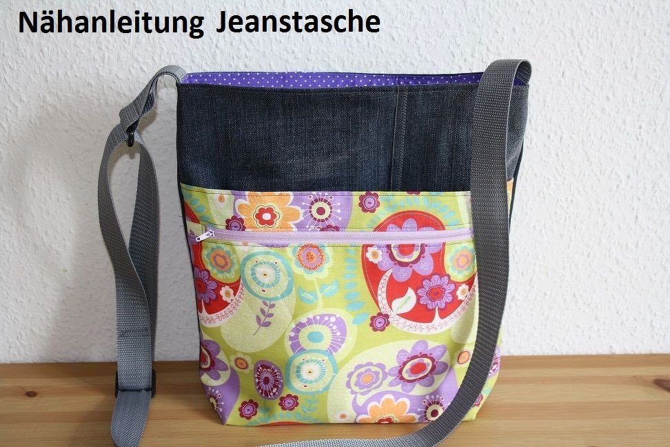 Selbstgenähte Umhängetasche aus Jeansstoff und buntem Blumenstoff mit lila Reißverschluss und grauem Schultergurt