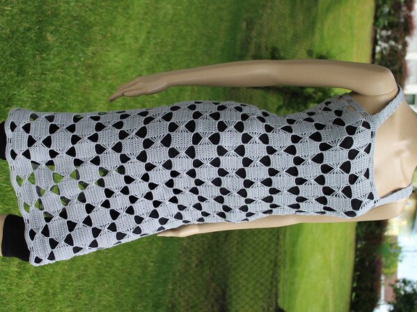 Hellgraues Häkelkleid mit durchbrochenem Muster auf einer Schaufensterpuppe vor Rasen