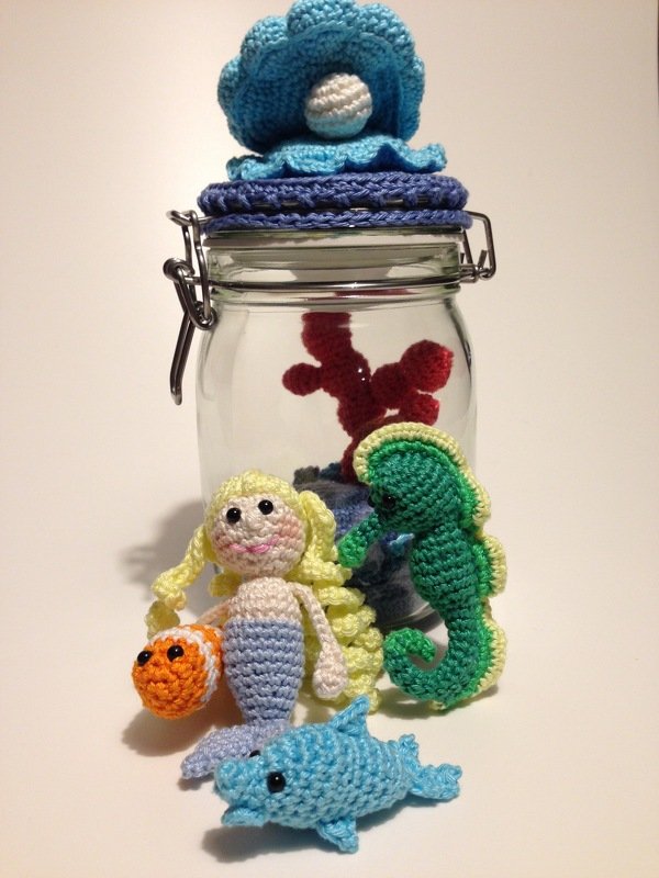 Häkel-Amigurumi Set: Meerjungfrau, Seepferdchen, Delfin und kleiner Fisch neben Glas