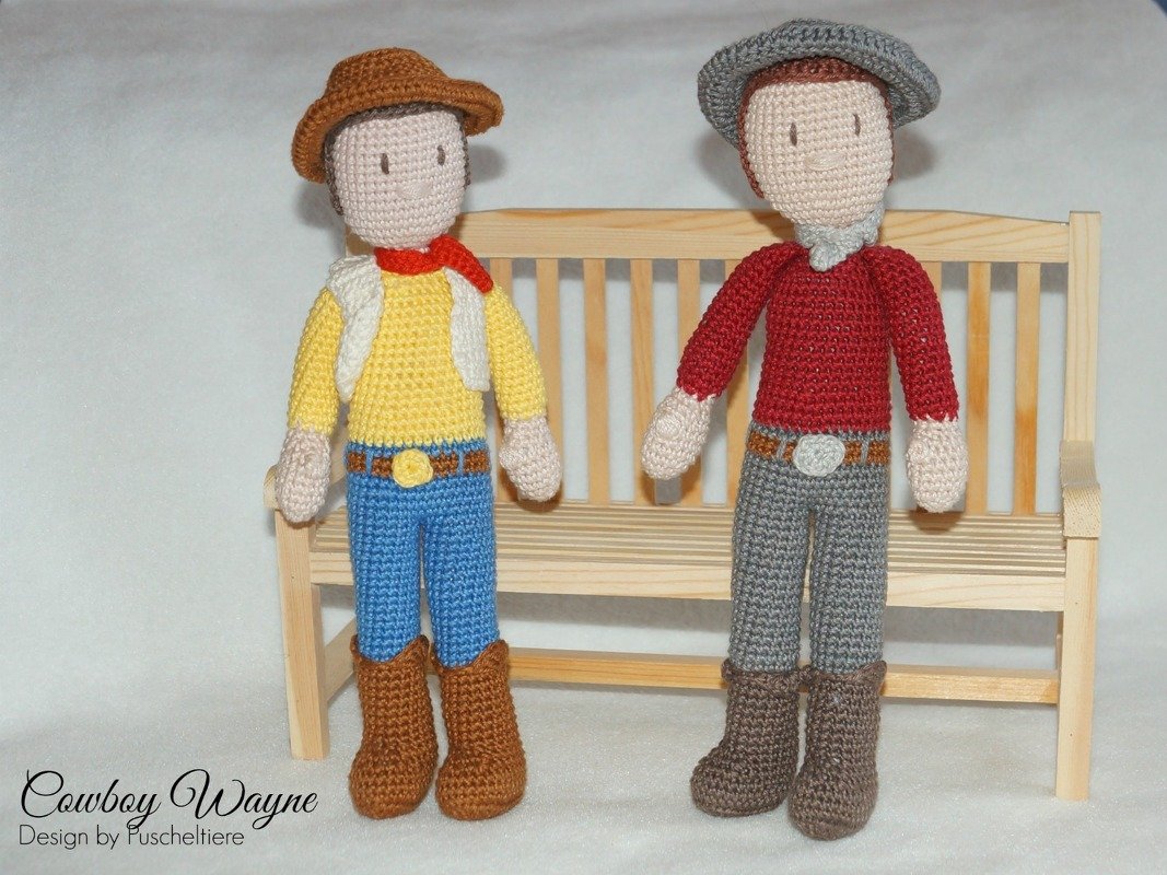 Zwei gehäkelte Amigurumi-Cowboypuppen vor einer Miniatur-Holzbank