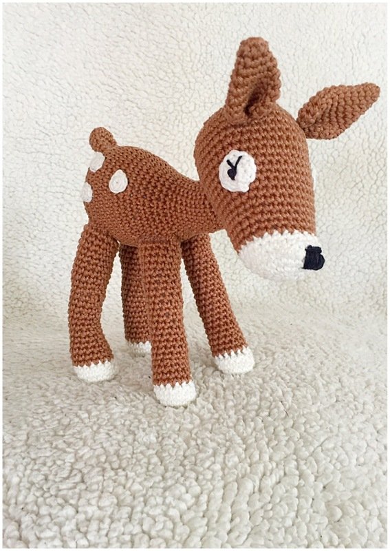 Gehäkeltes braunes Amigurumi-Rehkitz mit weißen Hufabschlüssen und Tupfen, zeigt Maschenstruktur